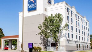 Ein Sleep Inn & Suites Gebäude mit auffälliger Beschilderung, einem überdachten Eingang und einem Baum davor.