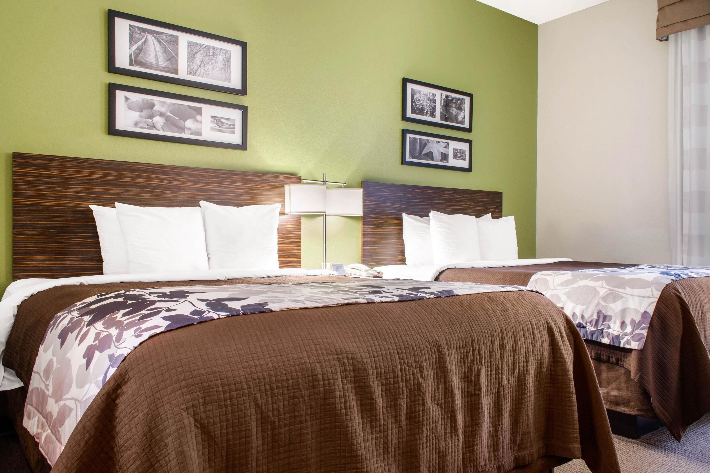 A hotel room with two beds, a wooden headboard, and green walls.
