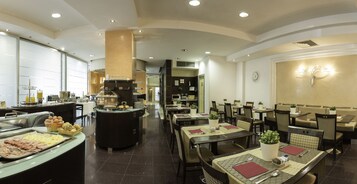 Een restaurantgedeelte in een hotel, met een buffet, zitmogelijkheden en een klok aan de muur.