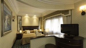 Une chambre d’hôtel avec un grand lit, un bureau avec une télévision, une chaise et une petite table.