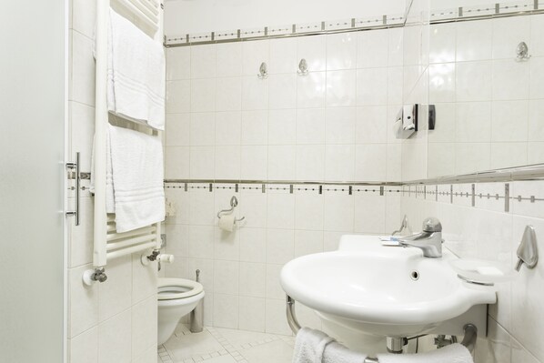 A bathroom with a toilet, sink, and towel rack. - Millennhotel (Bologna)