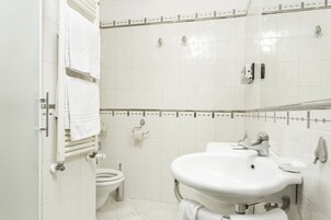 Un baño con inodoro, lavamanos y toallero.