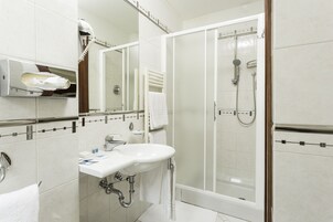 Een moderne badkamer met een douche met glazen wand, een witte wastafel en een handdoekhouder.