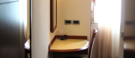 Una habitación de hotel con escritorio, silla y espejo.