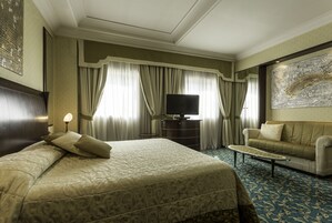 A hotel room with a large bed, a sofa, a television, and a coffee table.