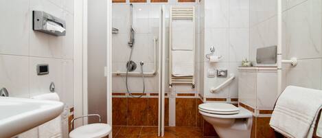 A bathroom with a shower, toilet, sink, and a towel rack.