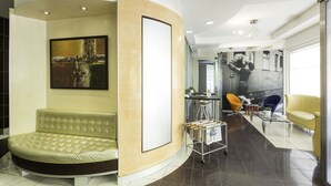 Un hall d’entrée moderne avec un espace salon aux lignes courbes, une grande peinture abstraite, une table basse en verre et une fresque représentant un train.