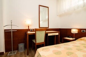 Een hotelkamer met een bed, bureau, stoel en nachtkastje.