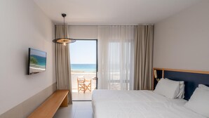 Ein Hotelzimmer mit Bett, Sitzbank, Fernseher und Blick auf den Strand.