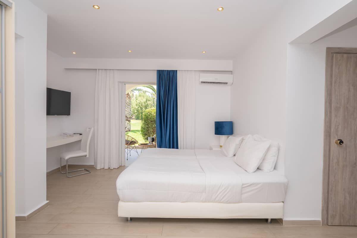 Un dormitorio moderno con una cama grande, un escritorio, un televisor y una puerta.
