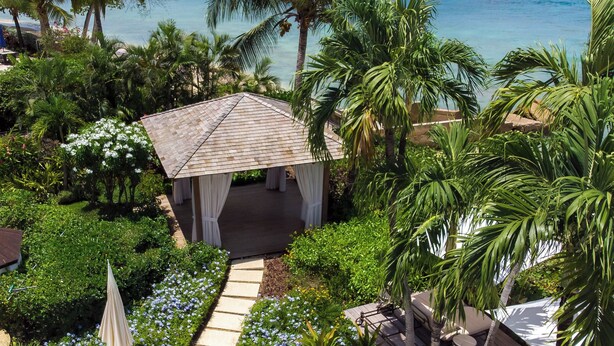 A gazebo with a tiled roof surrounded by lush greenery and a clear view of the ocean. - The House, An Autograph Collection All-Inclusive Resort - Adults Only (Paynes Bay)