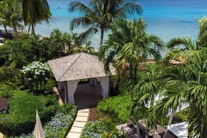 A gazebo with a tiled roof surrounded by lush greenery and a clear view of the ocean.