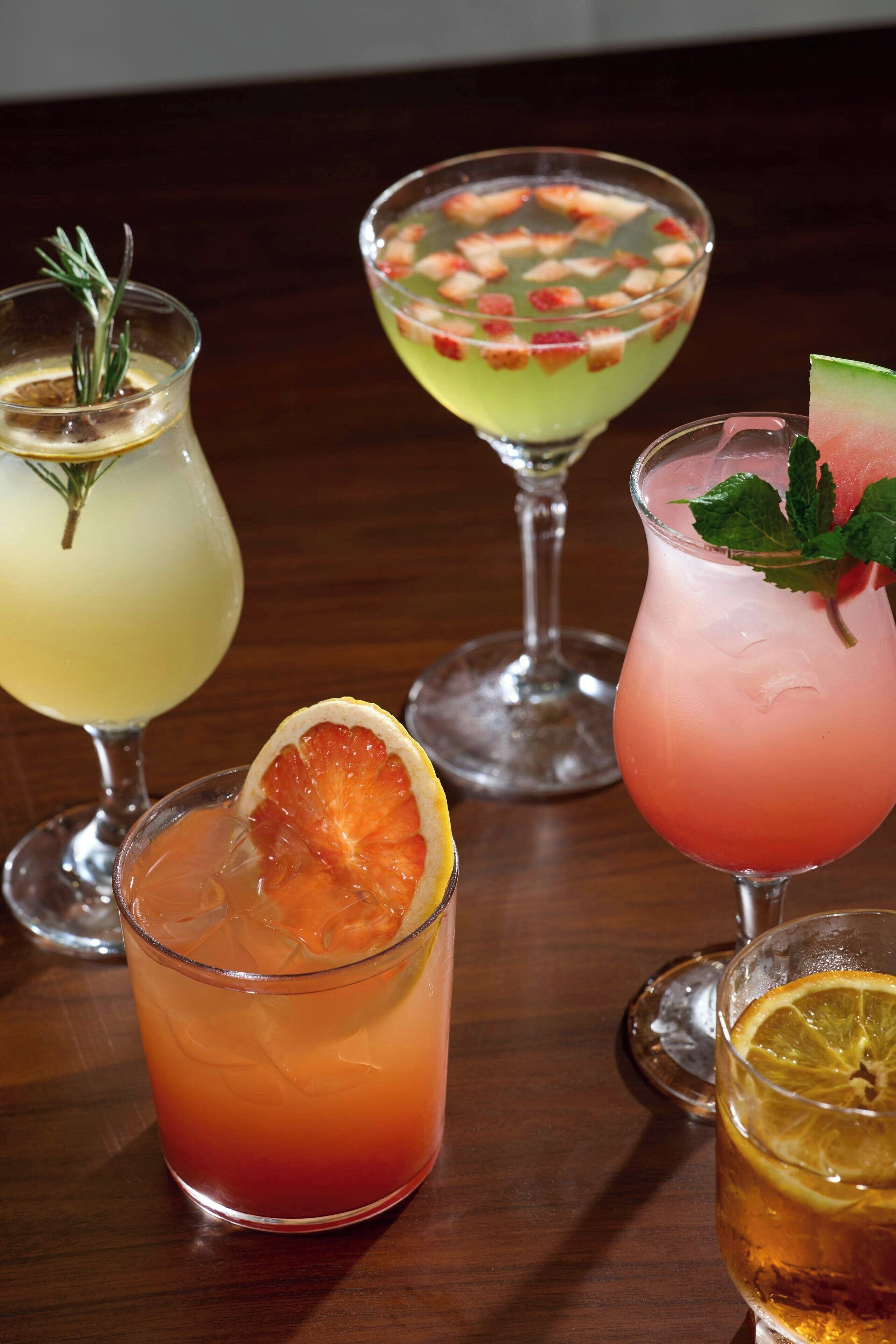 Four different cocktails on a wooden table.