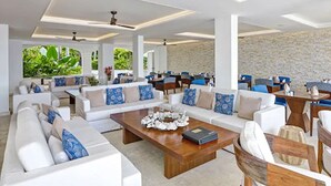 A spacious living area with white sofas, blue and beige cushions, a wooden coffee table, and a stone wall. - The House, An Autograph Collection All-Inclusive Resort - Adults Only (Paynes Bay)