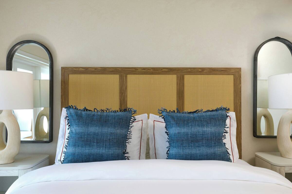 A hotel room with a large bed, two nightstands, and a headboard with a woven panel.