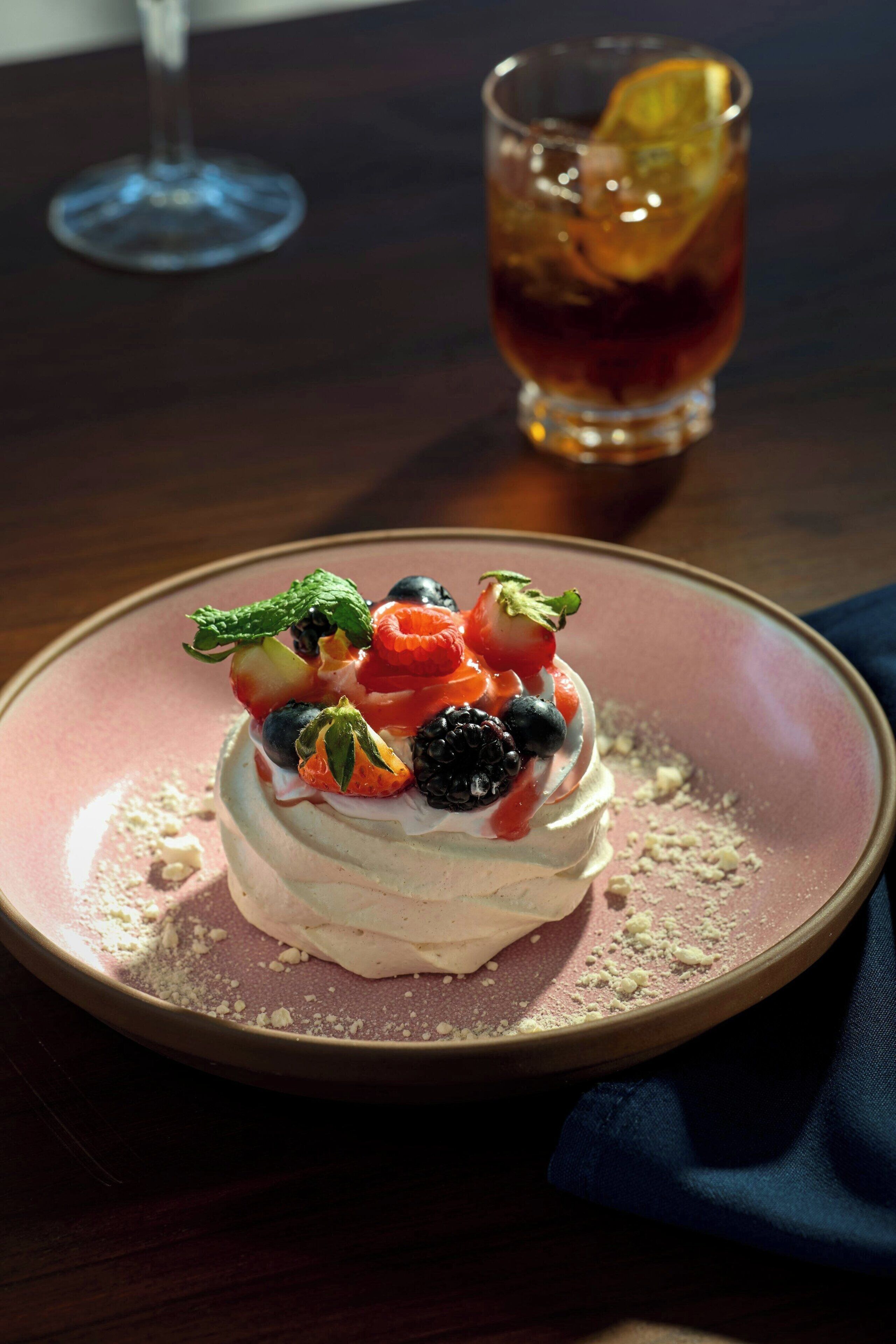 A dessert on a pink plate with a glass of iced tea in the background.