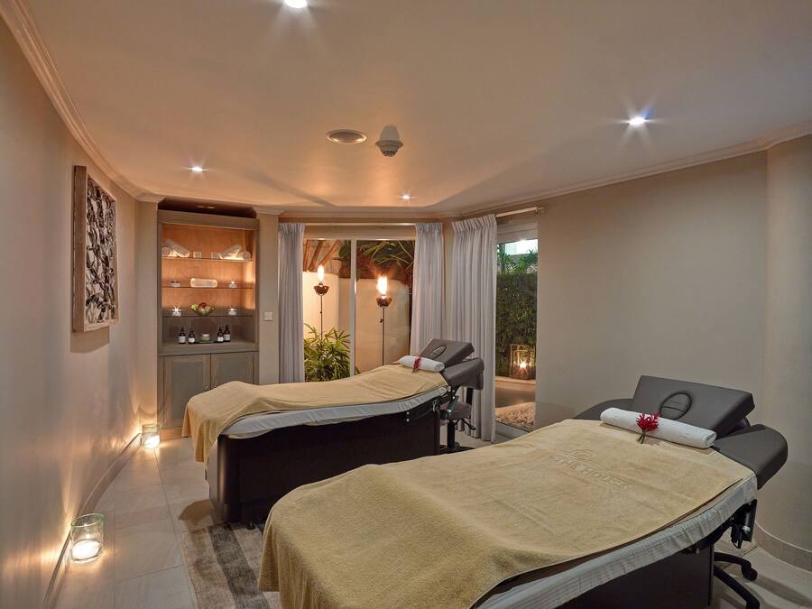 Un cuarto de spa con dos camillas de masaje, un mostrador de recepción y vista al exterior.