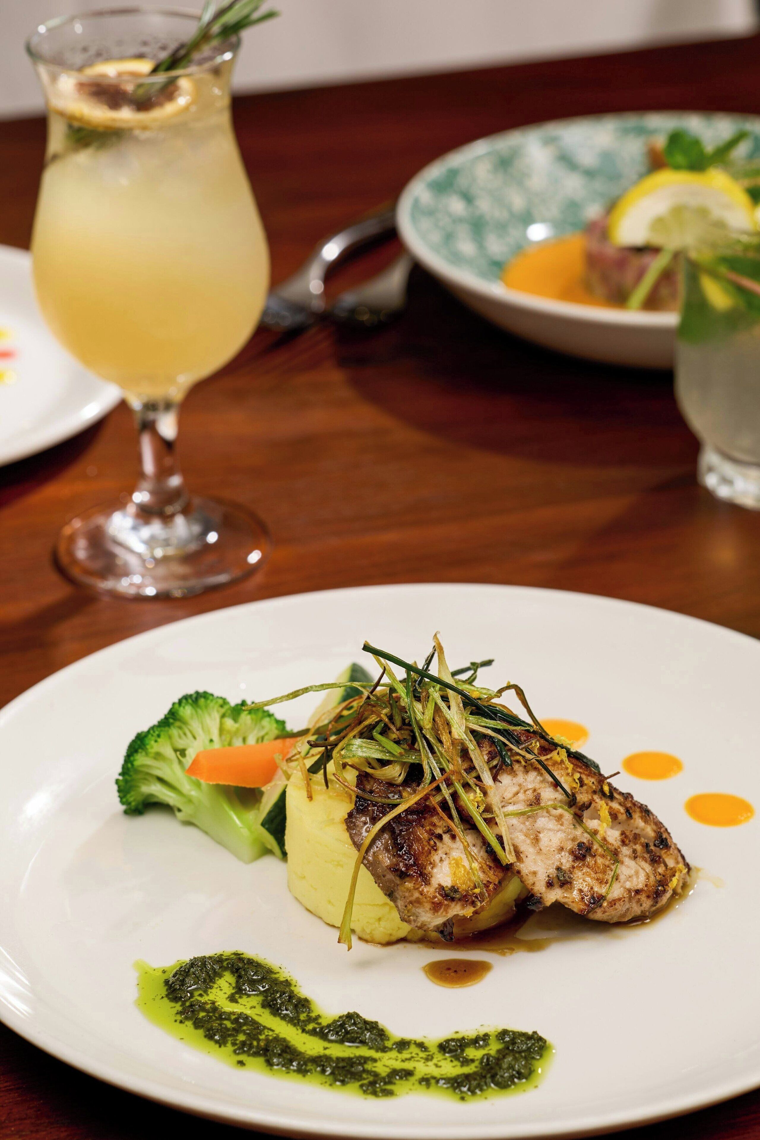 A plate of food with a glass of drink in the background.