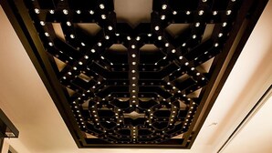 Un salon moderne avec un plafond au design géométrique, une table centrale et un canapé.