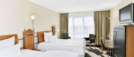 A hotel room with two beds, a desk, a chair, a television, and a lamp.