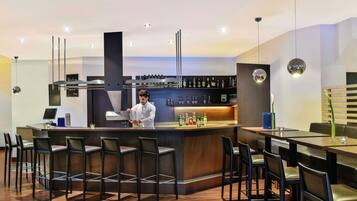 Eine moderne Bar mit einer Theke, einem Koch, der Getränke zubereitet, und einer Sitzgelegenheit mit Stühlen und Tischen.