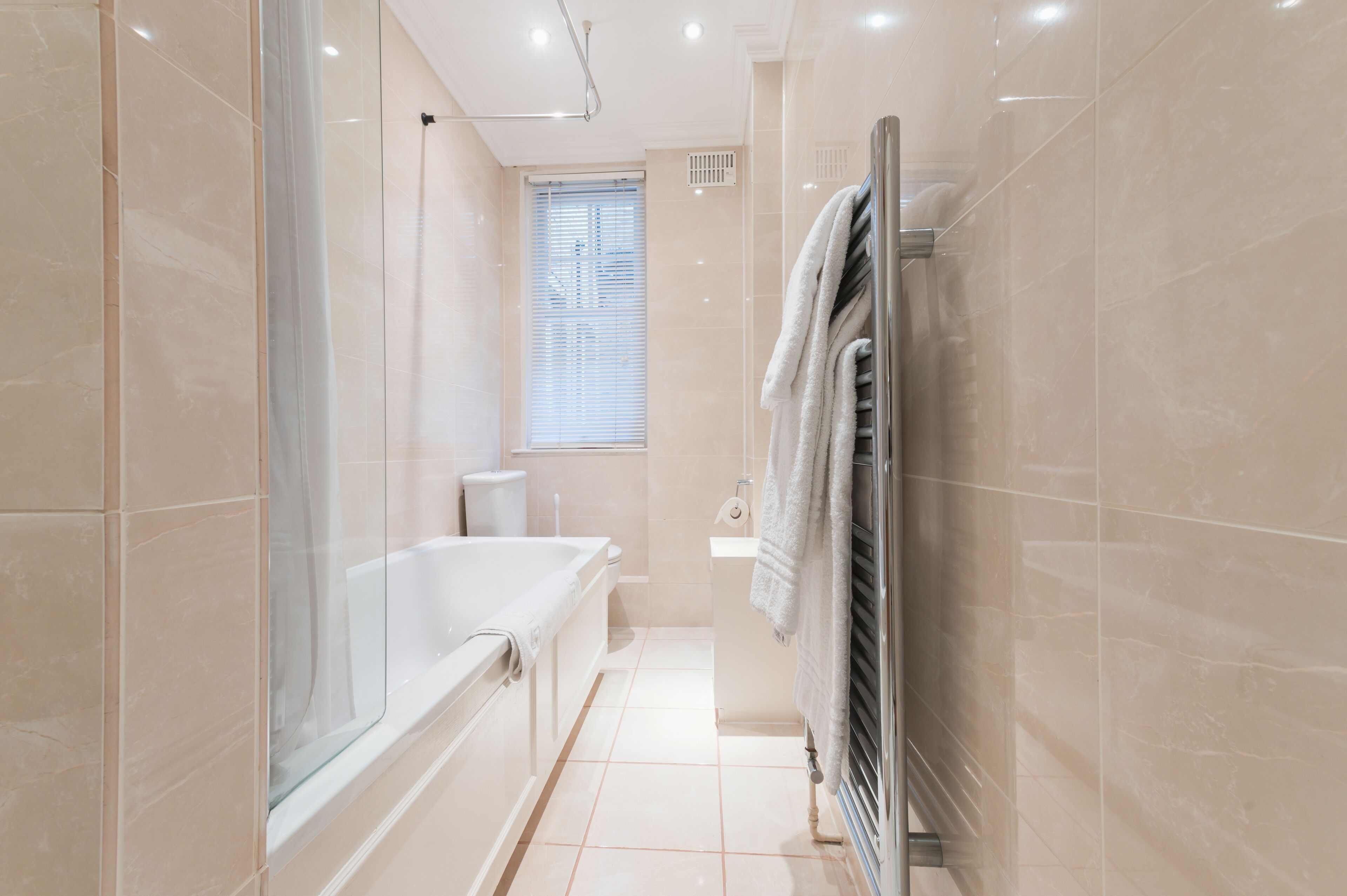 Un baño moderno con bañera, cabina de ducha con mampara de vidrio y un perchero para toallas.