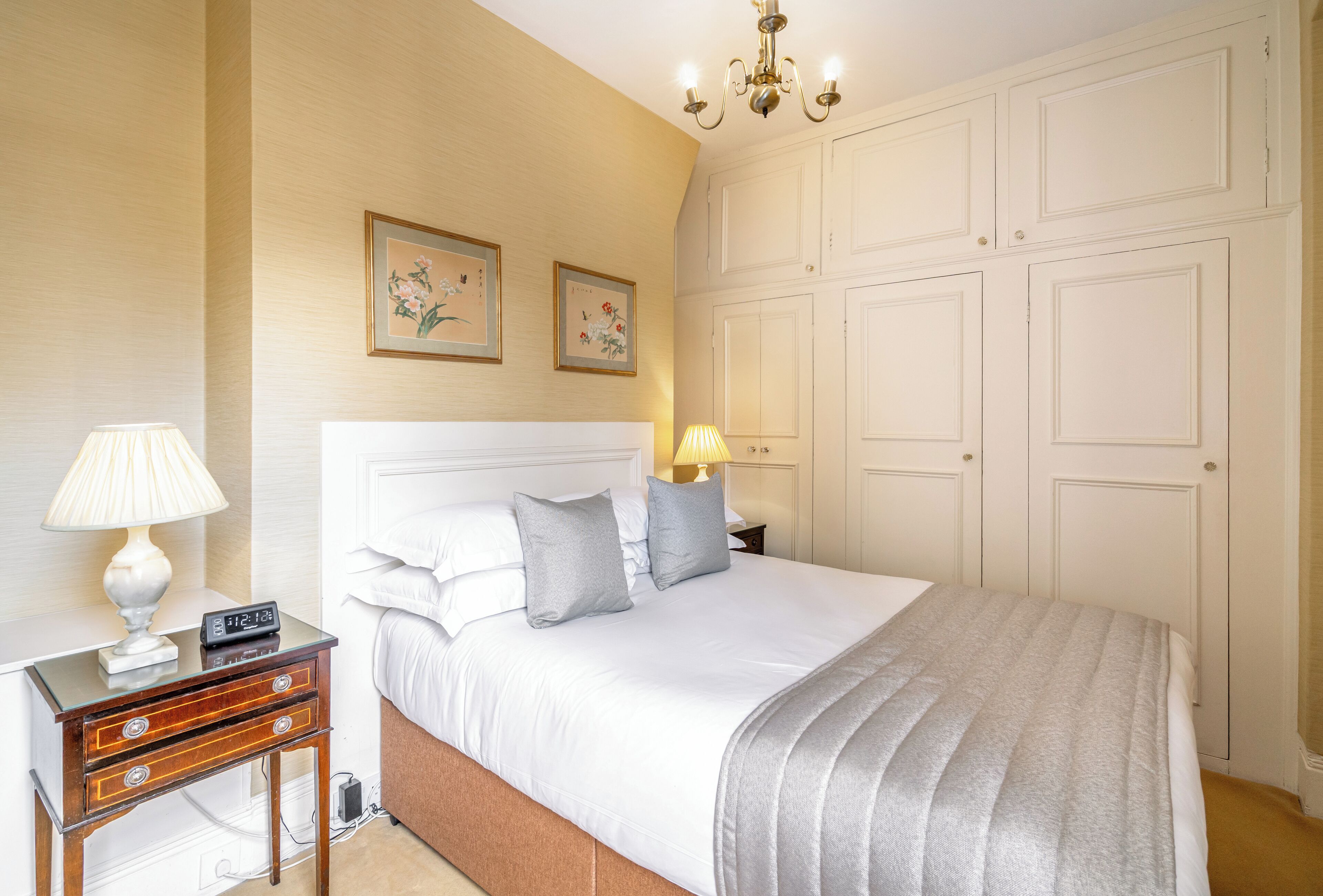 Een slaapkamer met een bed, nachtkastjes, lampen en een kledingkast.