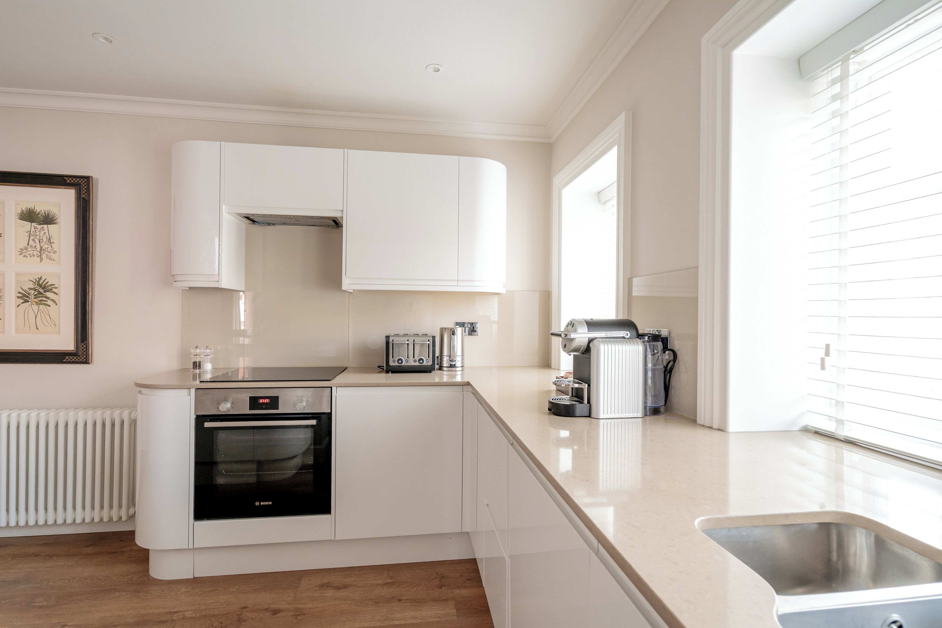 A modern kitchen with white cabinetry, a Bosch oven, a toaster, and a coffee maker.