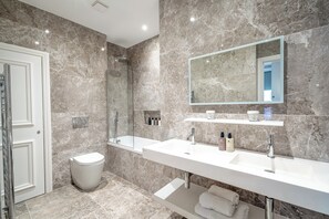 Une salle de bain moderne avec deux lavabos, un grand miroir et une douche.