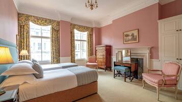 A bedroom with two beds, a dresser, a chair, a desk, and a fireplace.