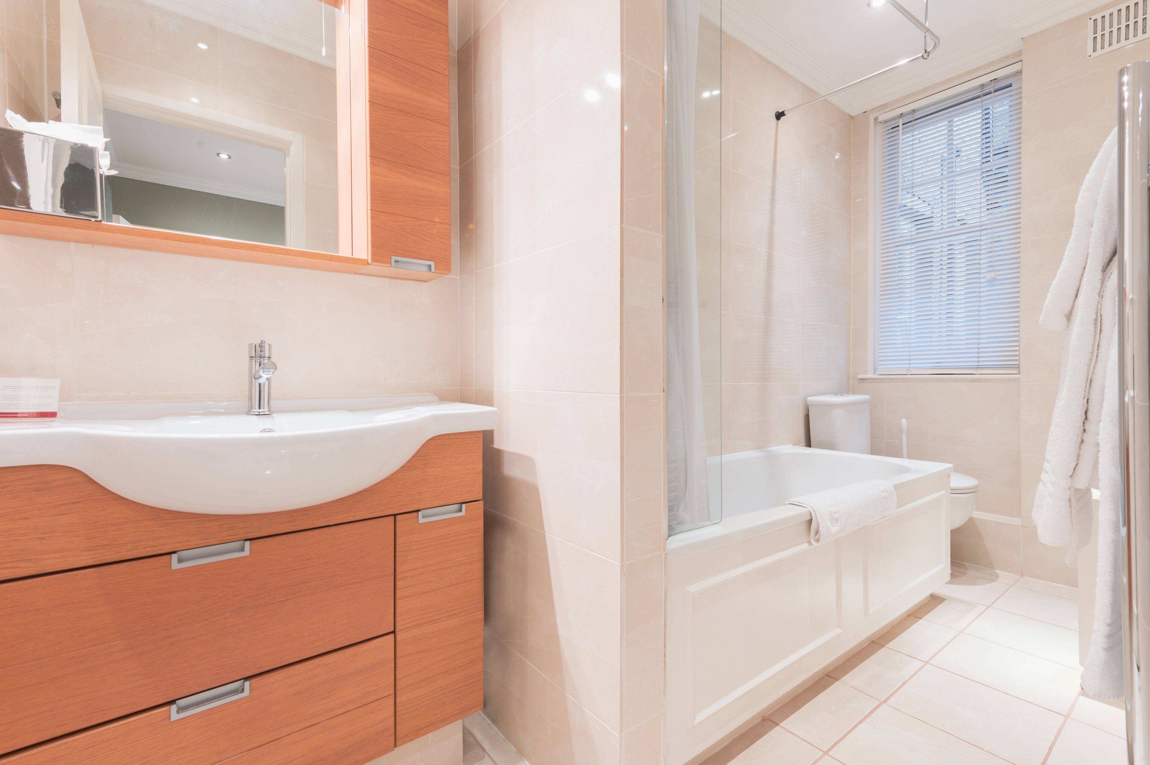 A modern bathroom with a large sink, vanity, bathtub, and shower.
