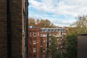 Un immeuble à plusieurs étages, avec des façades en briques, de nombreuses fenêtres et une cheminée bien visible.