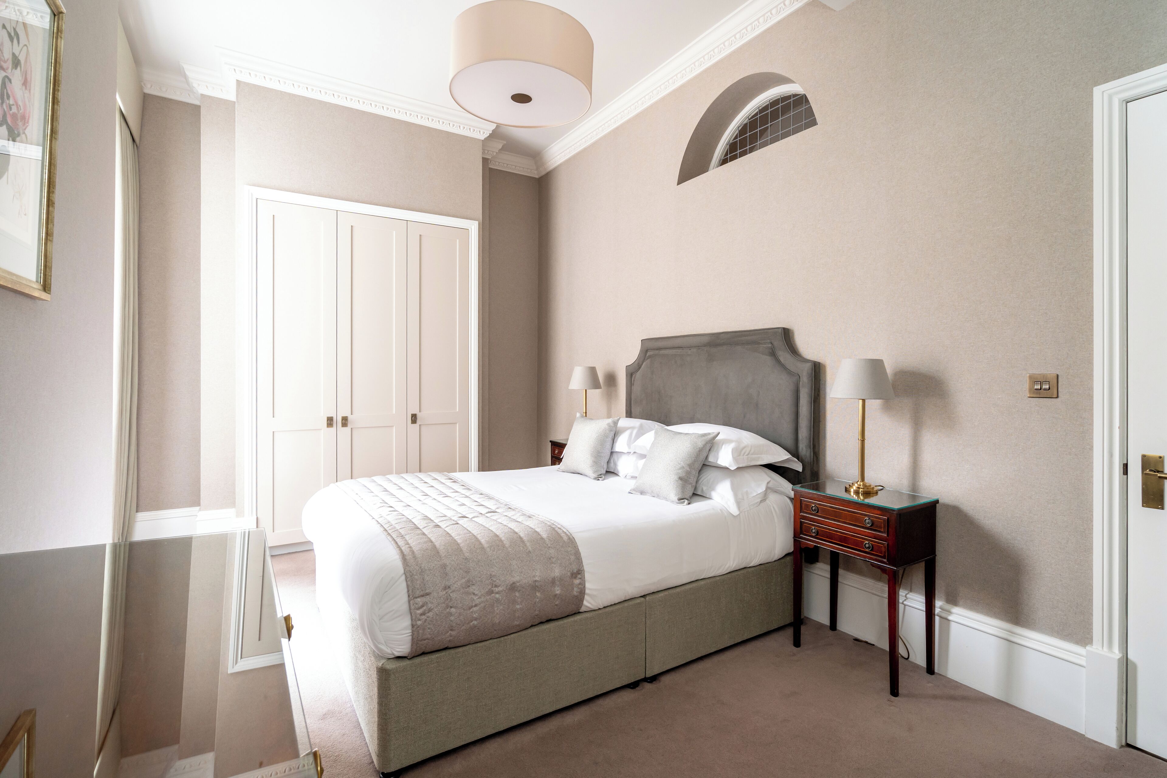 A bedroom with a large bed, bedside tables, a wardrobe, and a ceiling light.