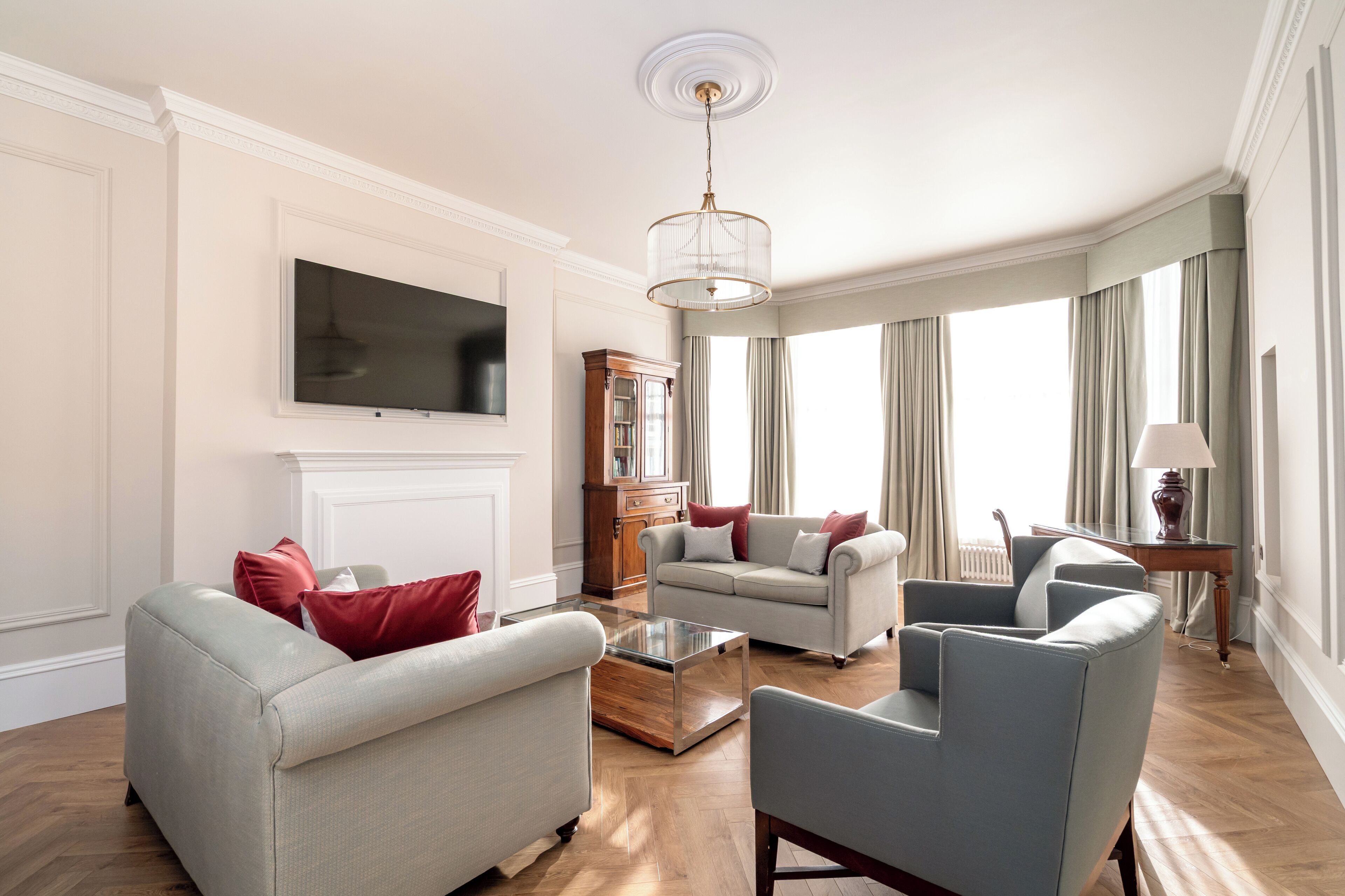 Amplia sala de estar con televisor de pantalla plana, una mesa de centro de madera y diversas opciones de asientos, incluyendo sofás y sillones.