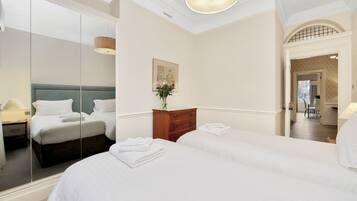 A hotel room with two beds, a wooden dresser, a mirror, and a painting on the wall.