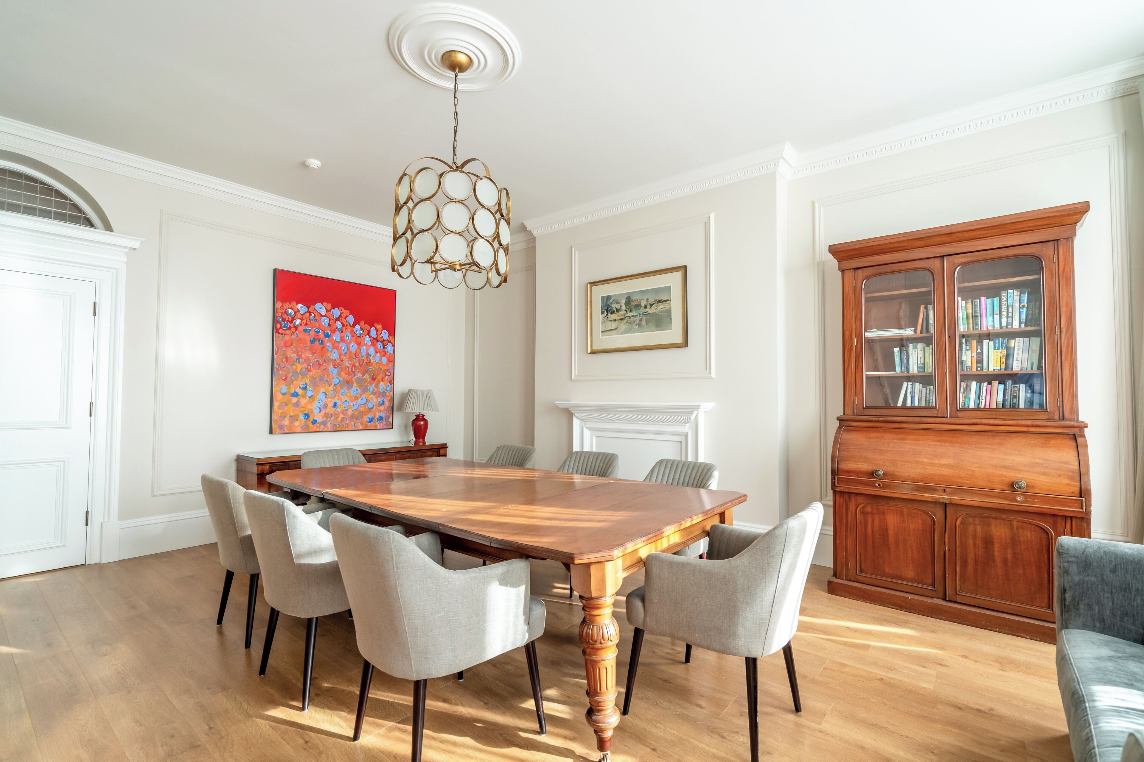 Comedor con mesa de madera y seis sillas, una estantería y una chimenea.