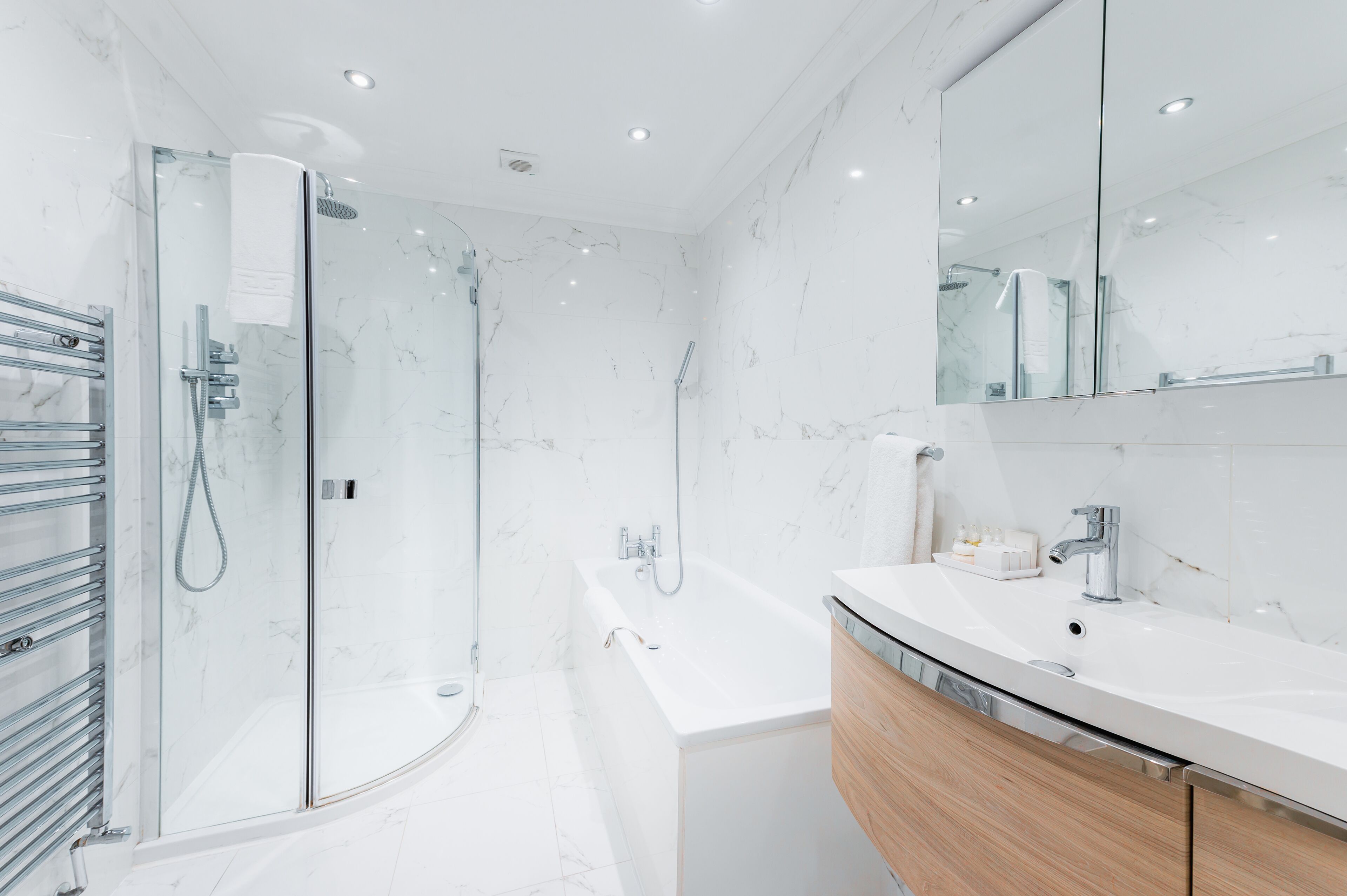 A modern bathroom with a glass shower enclosure, a standalone bathtub, and a vanity with a mirror.