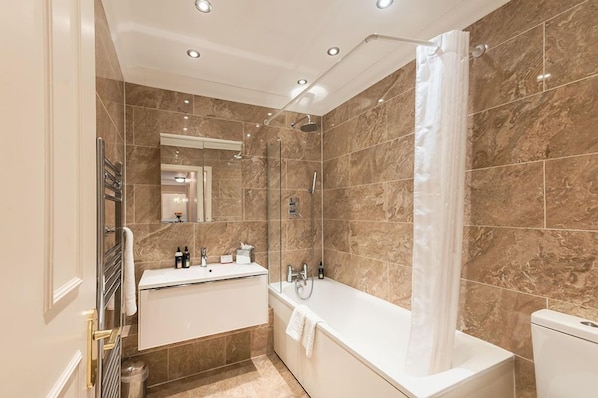 Une salle de bain moderne équipée d’une baignoire, d’une douche et d’un meuble-lavabo.