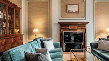 Un salon avec un canapé de couleur turquoise, un meuble en bois, une cheminée et un tableau encadré au mur.