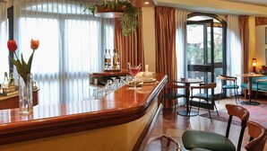 Un bar de hotel con mostrador de madera, taburetes y un área de estar con mesas y sillas.