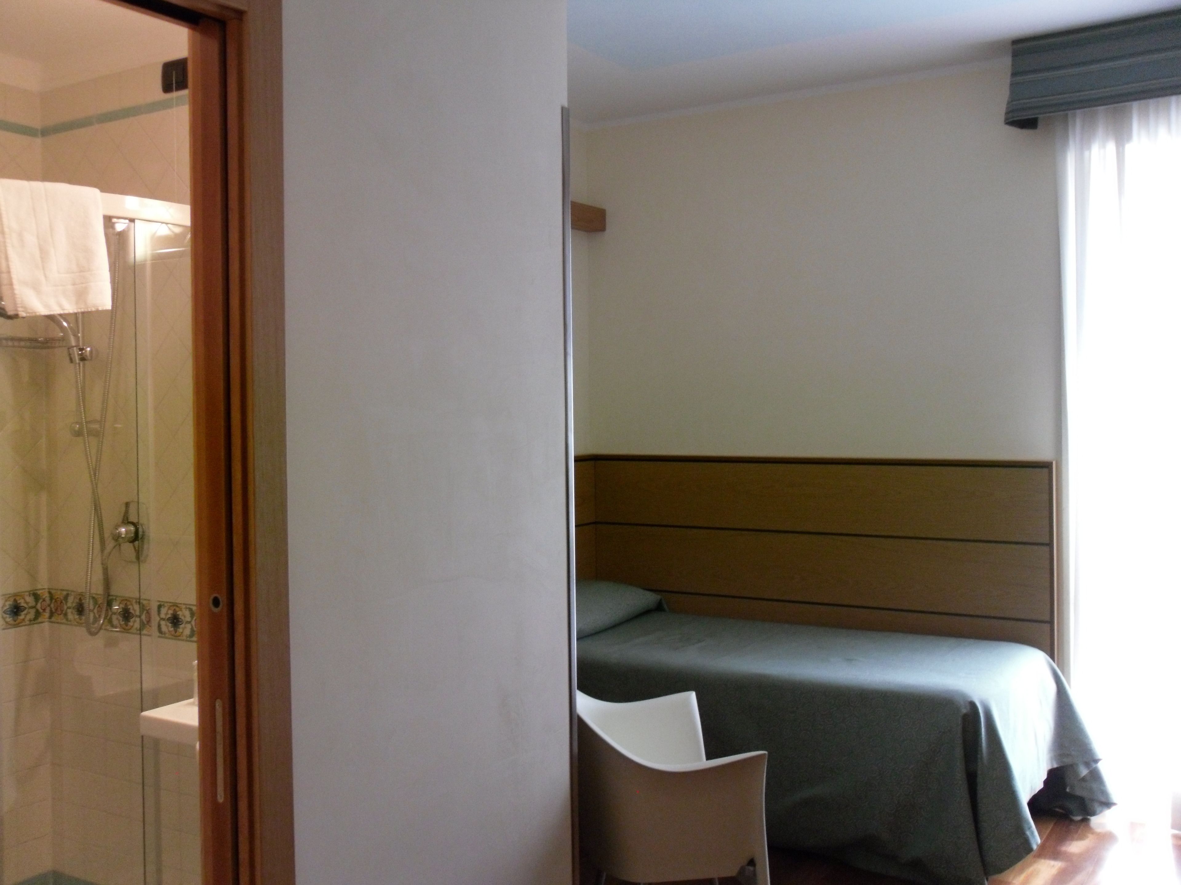 A hotel room with a shower, a bed, and a chair.