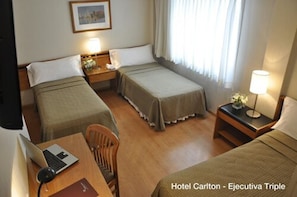 Een hotelkamer met twee bedden, een bureau met een laptop en een stoel.