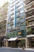 A multi-story hotel with balconies, a prominent vertical sign, and a storefront with the name "HOTEL CARLTON".
