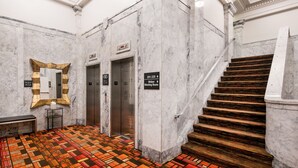 A marble-floored lobby with a patterned carpet, an elevator, and a staircase. - Hampton Inn & Suites Ogden (Ogden)