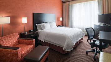 Una habitación de hotel con una cama grande, un escritorio con una silla, un sofá y un televisor.