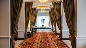 A hallway with patterned carpet, draped curtains, and a chandelier. - Hampton Inn & Suites Ogden (Ogden)