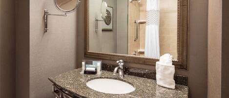 A bathroom with a granite countertop sink, a mirror, and a towel rack.