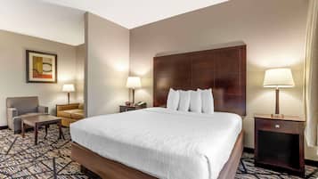 Une chambre d’hôtel avec un grand lit, deux tables de chevet avec des lampes, une chaise et une petite table.
