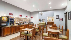 A restaurant with wooden furniture, a counter with a coffee machine, and a chandelier. - Best Western Plus Hobby Airport Inn & Suites (Houston)