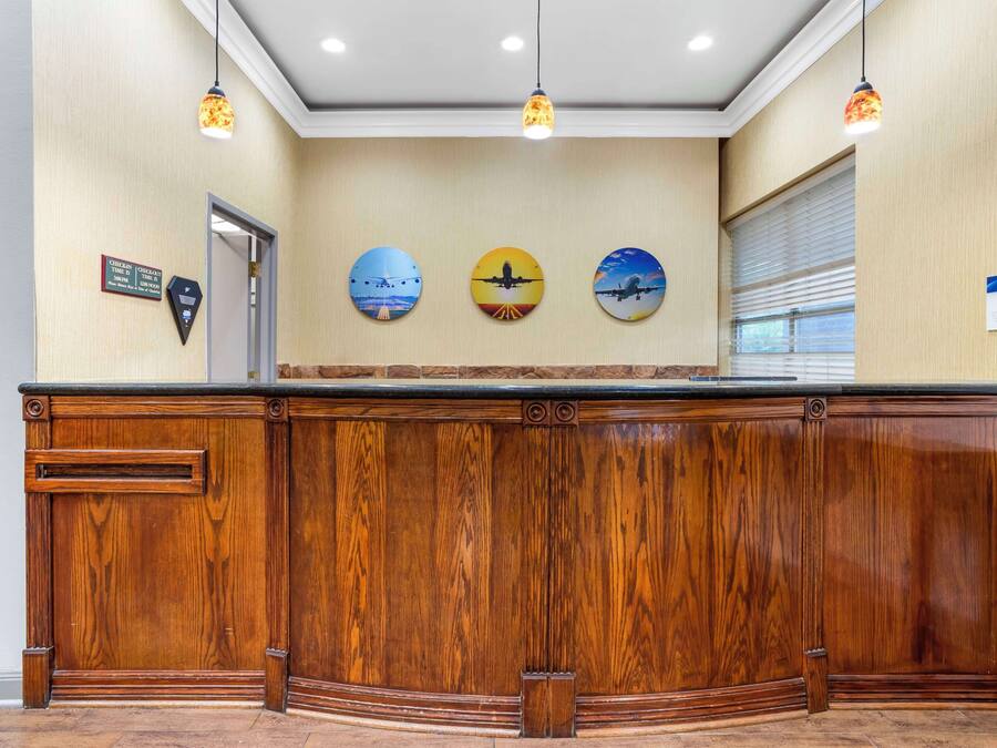 A reception desk with a wooden finish, three wall-mounted clocks, and a window with blinds.